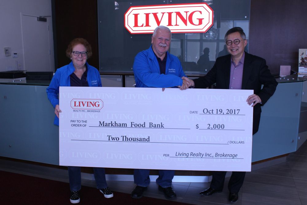 Stephen Wong, president of the Living Group of Companies, hands over a $2000 cheque following a successful food drive